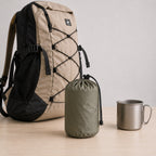 Inflatable camping pillow packed in a compact storage bag beside a hiking backpack